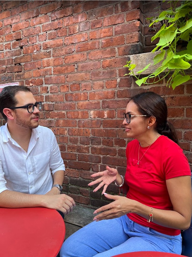 Josué in conversation with a student at an outdoor table in New York